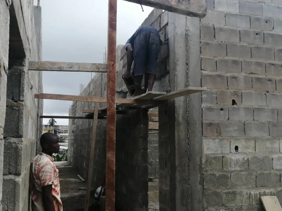 Ouvrier sur échafaudage lors de la reprise des murs, chantier de Kribi